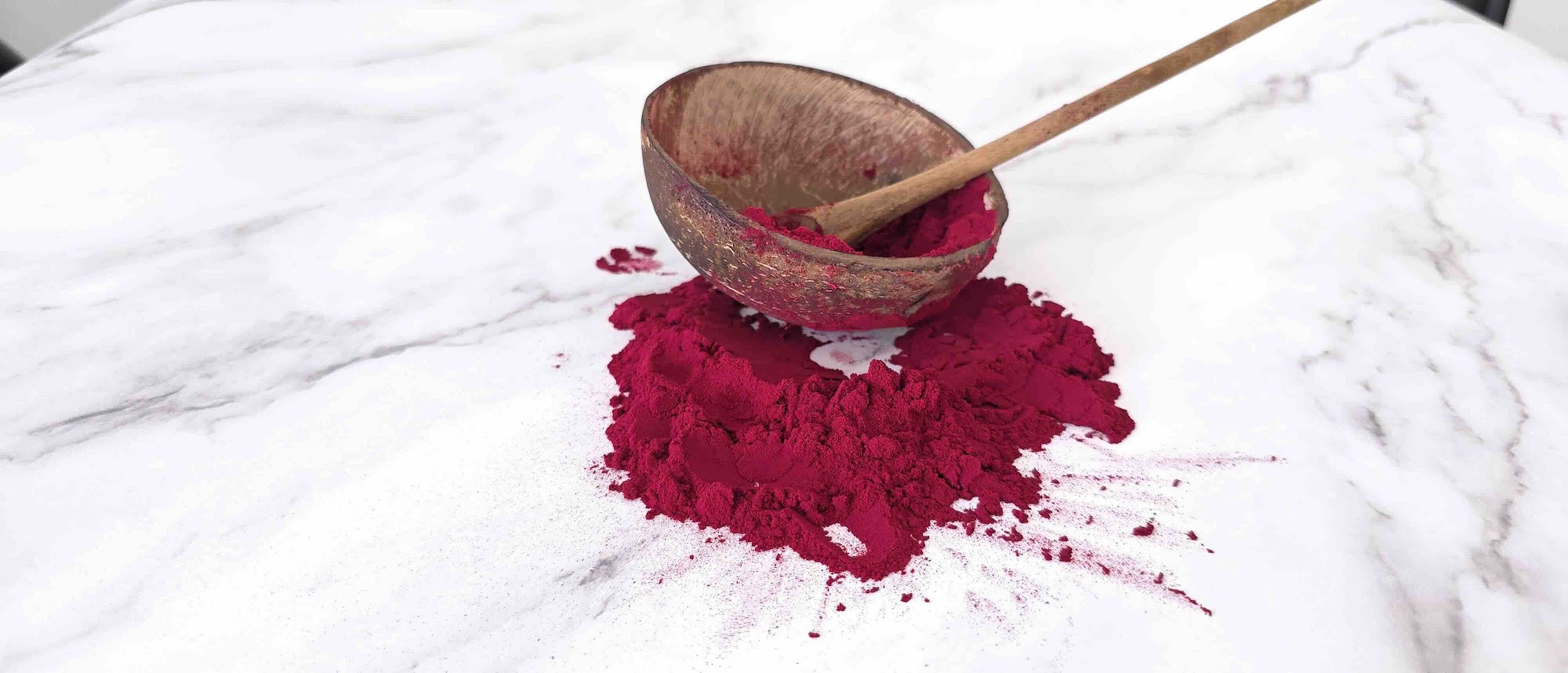 Black carrot Red powder in a wooden bowl on a white marble surface