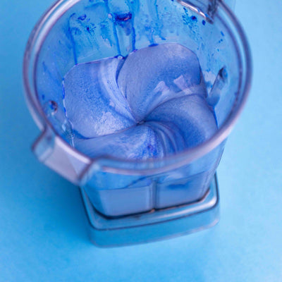 Blue swirling liquid in a blender on a blue background