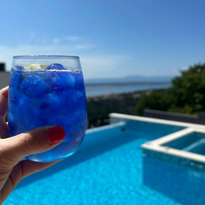 Blue spirulina ice cubes in a glass by the pool – vibrant natural blue drink coloring
