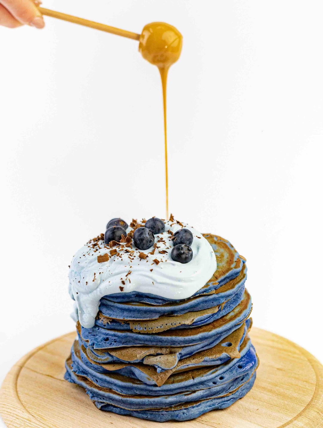 Blue Spirulina Powder pancakes with honey and blueberries as natural blue food coloring inspiration