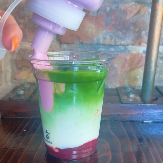 Matcha latte with pink cloud foam made from Dragon Fruit Powder, served in a clear cup.