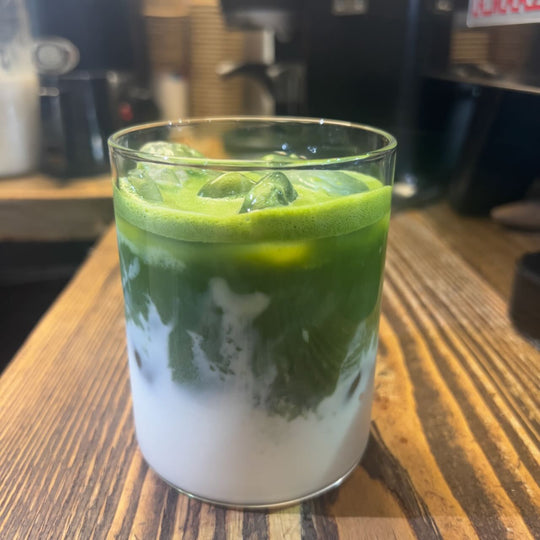 Yes Superfood Matcha powder prepared as an iced matcha latte, showing its vibrant green color and smooth layered texture.